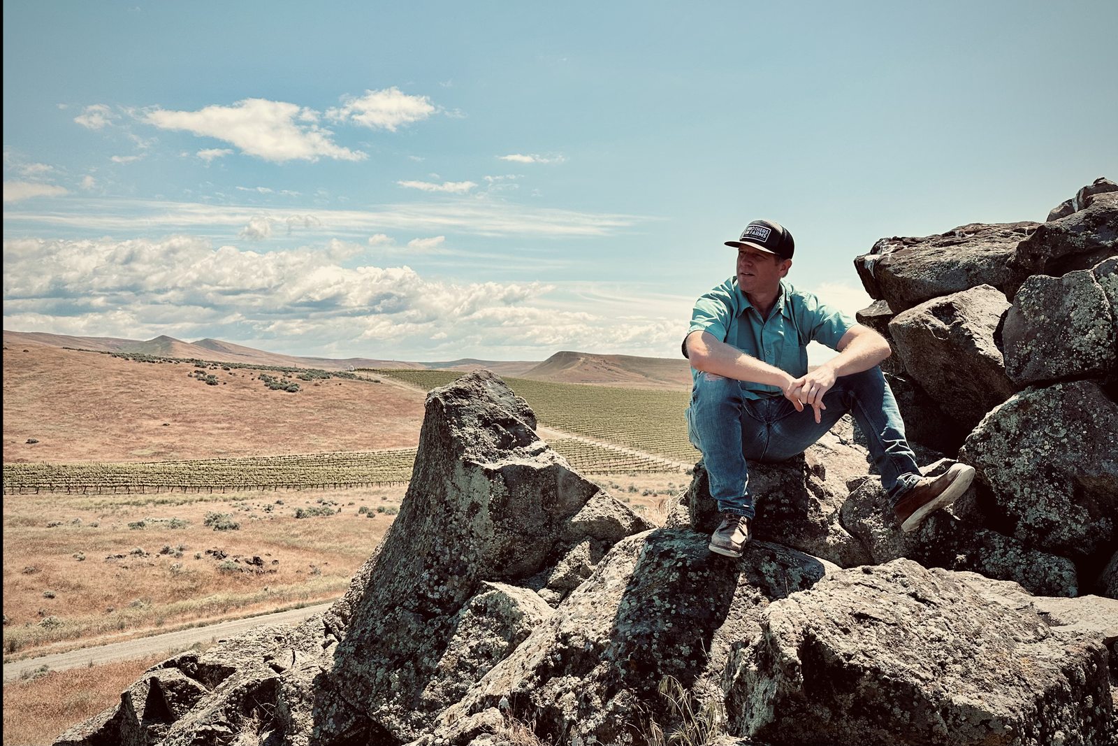 Andrew Schultz sitting on the rocks above the vineyard
