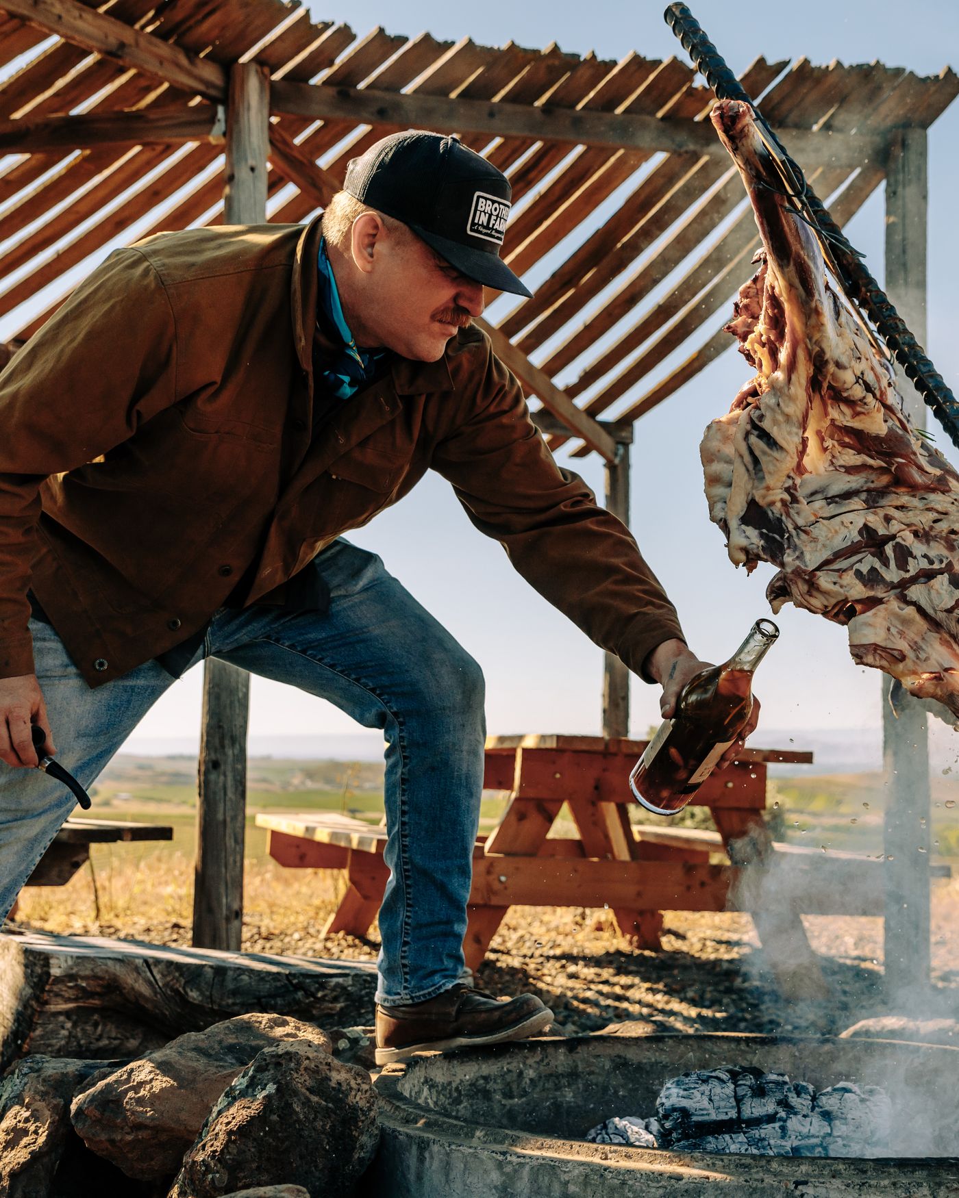 Basting the whole lamb with a bottle over the fire on the Butte
