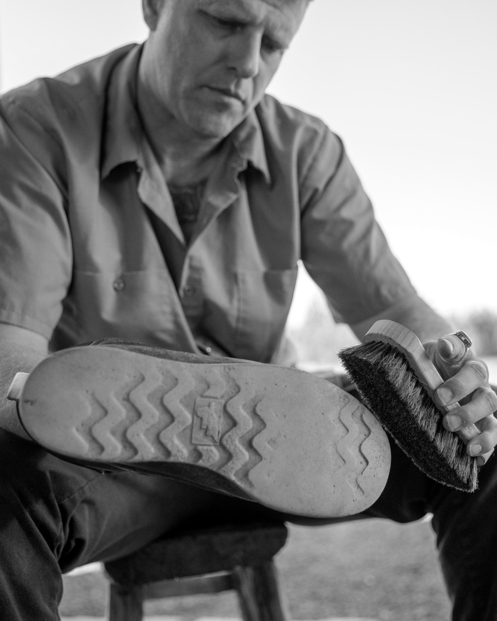 Andrew Schultz brushing off a work boot